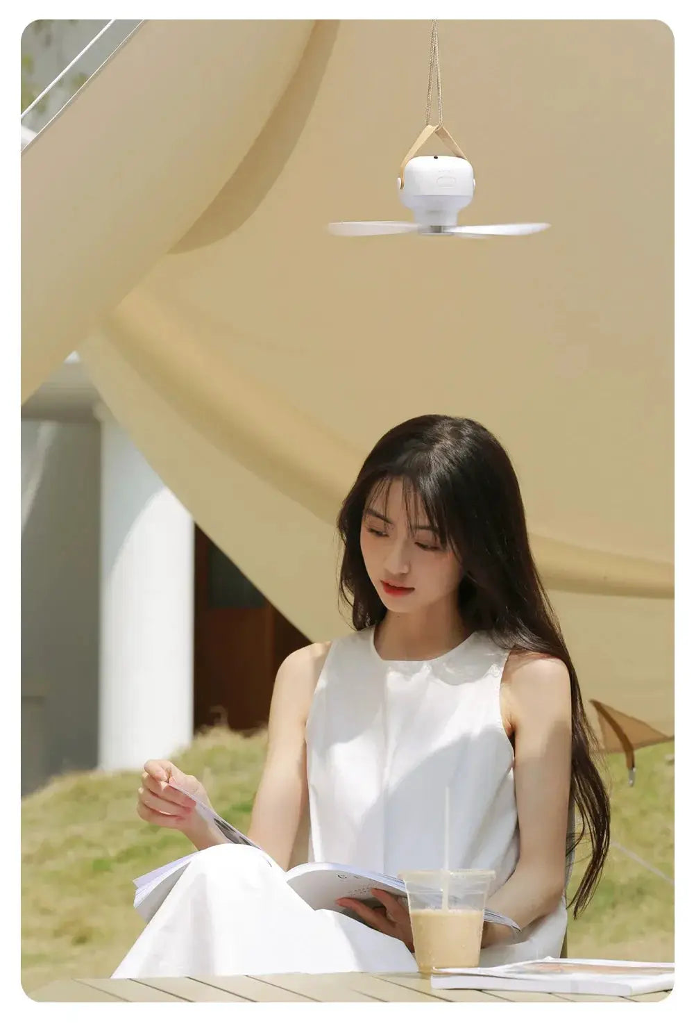 Portable wireless mini ceiling fan, white, hanging by strap in outdoor setting