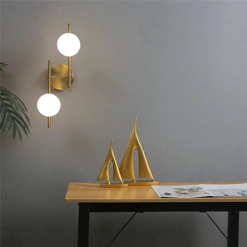 Modern gold LED wall sconce with double milky-glass globe bulbs on brass mount