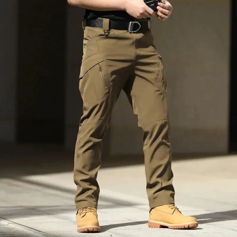 Men's tactical cargo pants in tan, softshell stretchy fabric with multiple pockets and button fly