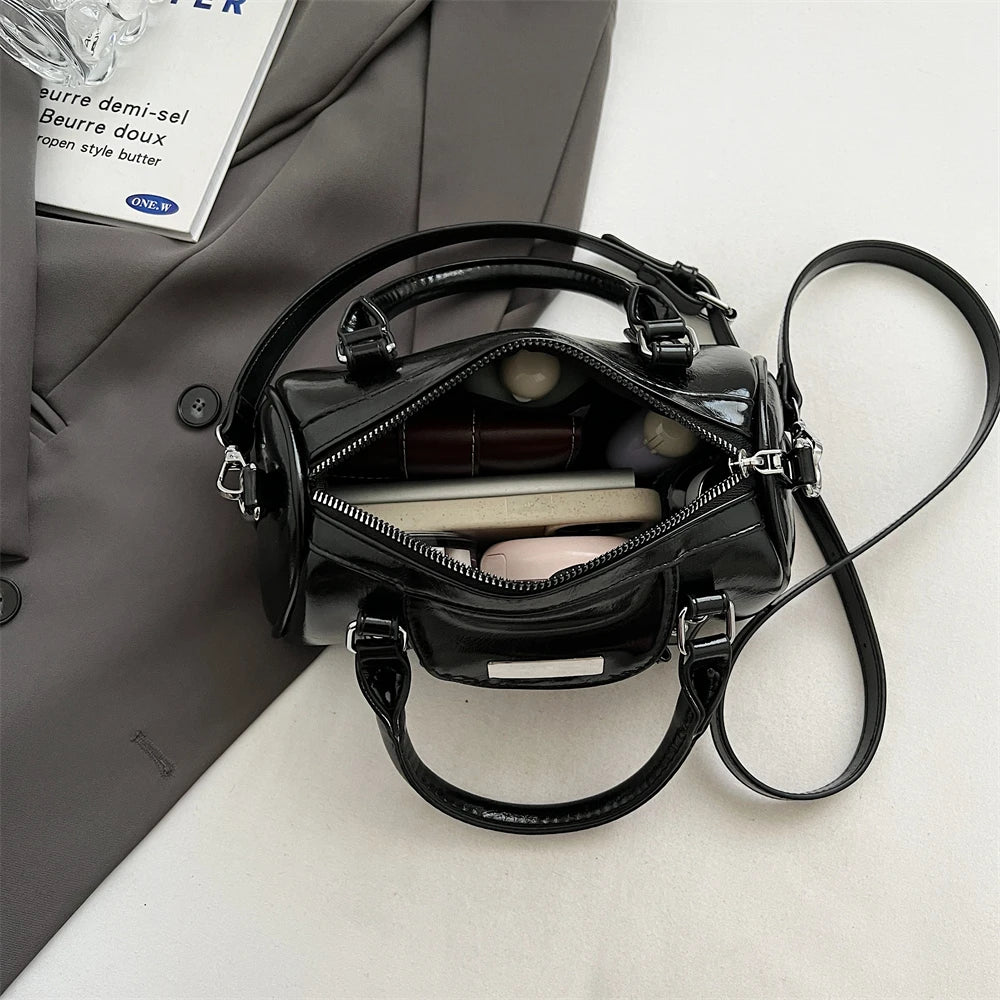 Mini top-handle bag by Simples Market; black PU leather with detachable strap, open zipper reveals compact interior.