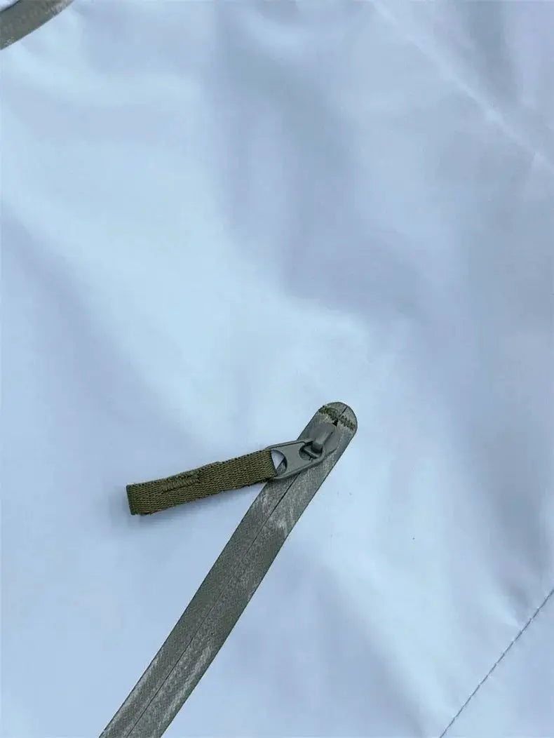 Outdoors jacket zipper pull with olive webbing strap on gray soft shell fabric
