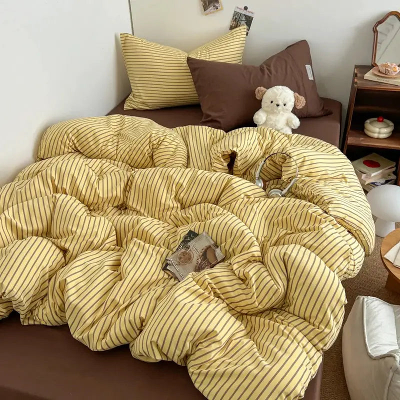 Bedding set with blue-striped yellow duvet cover, pillowcases and bedsheet on a bed