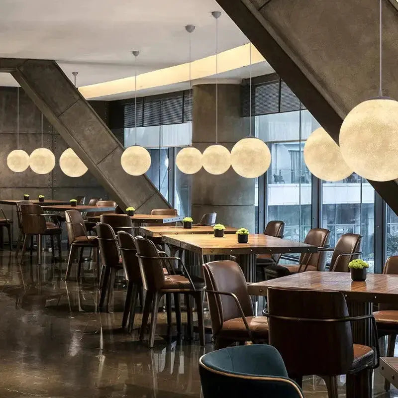 Nordic Moon LED pendant lights, multiple warm glass globes hanging in a modern cafe.