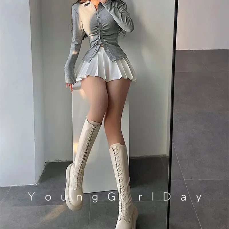 Pleated skirt with shorts, white high-waist A-line mini, paired with cream knee-high lace-up boots