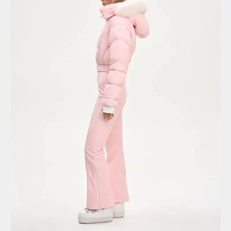 One-piece ski suit for women by Simples Market in pink with faux fur hood and high-waist belt.