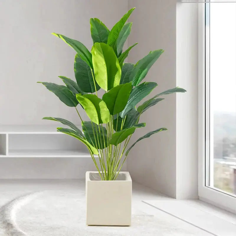 Artificial tropical plant with broad green leaves in a square white pot for home decor