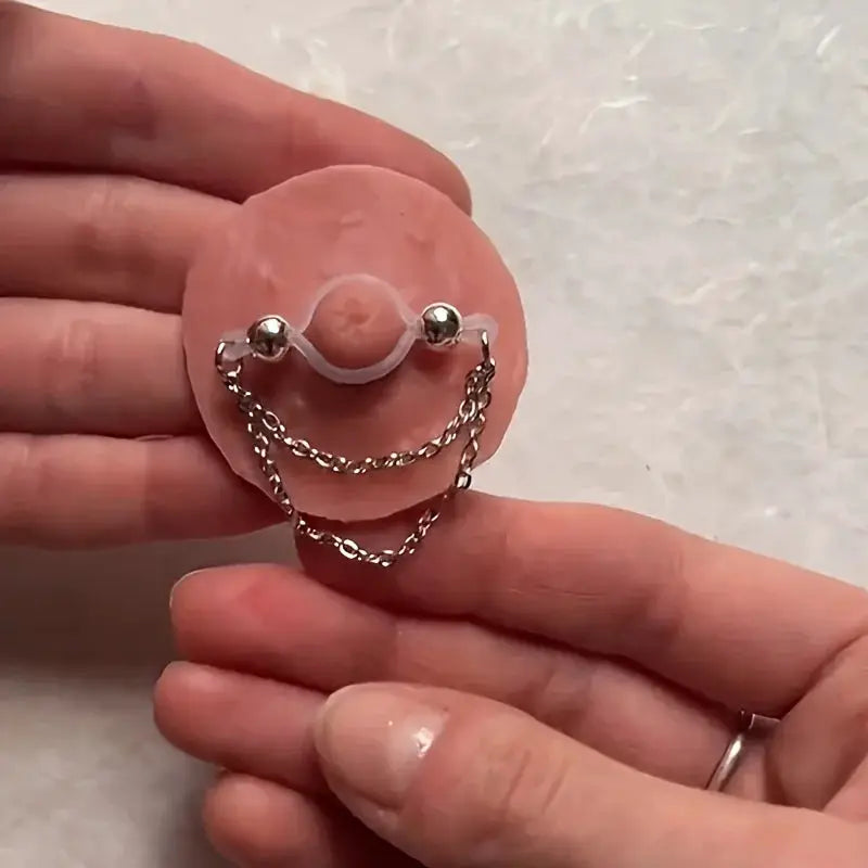 1 pair of adjustable fake nipple rings with pink acrylic disk and sparkling accents, connected by silver chains