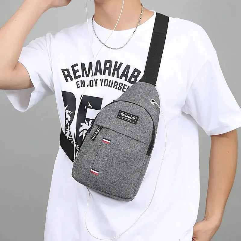 Chest bag in gray fabric with black crossbody strap and front zip pocket