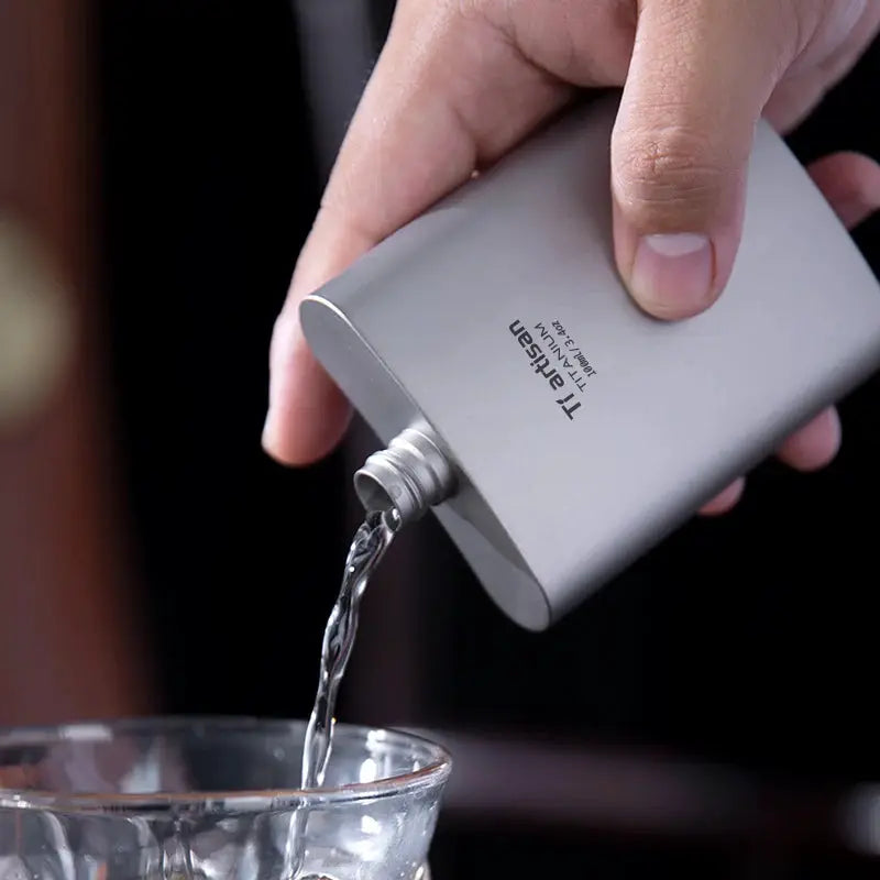 Tiartisan titanium hip flask 100ml, silver metal, pouring into a glass.