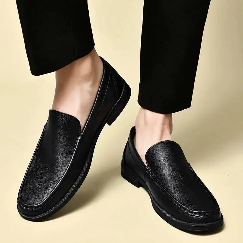 Pair of black leather men's slip-on loafers for office and formal wear.