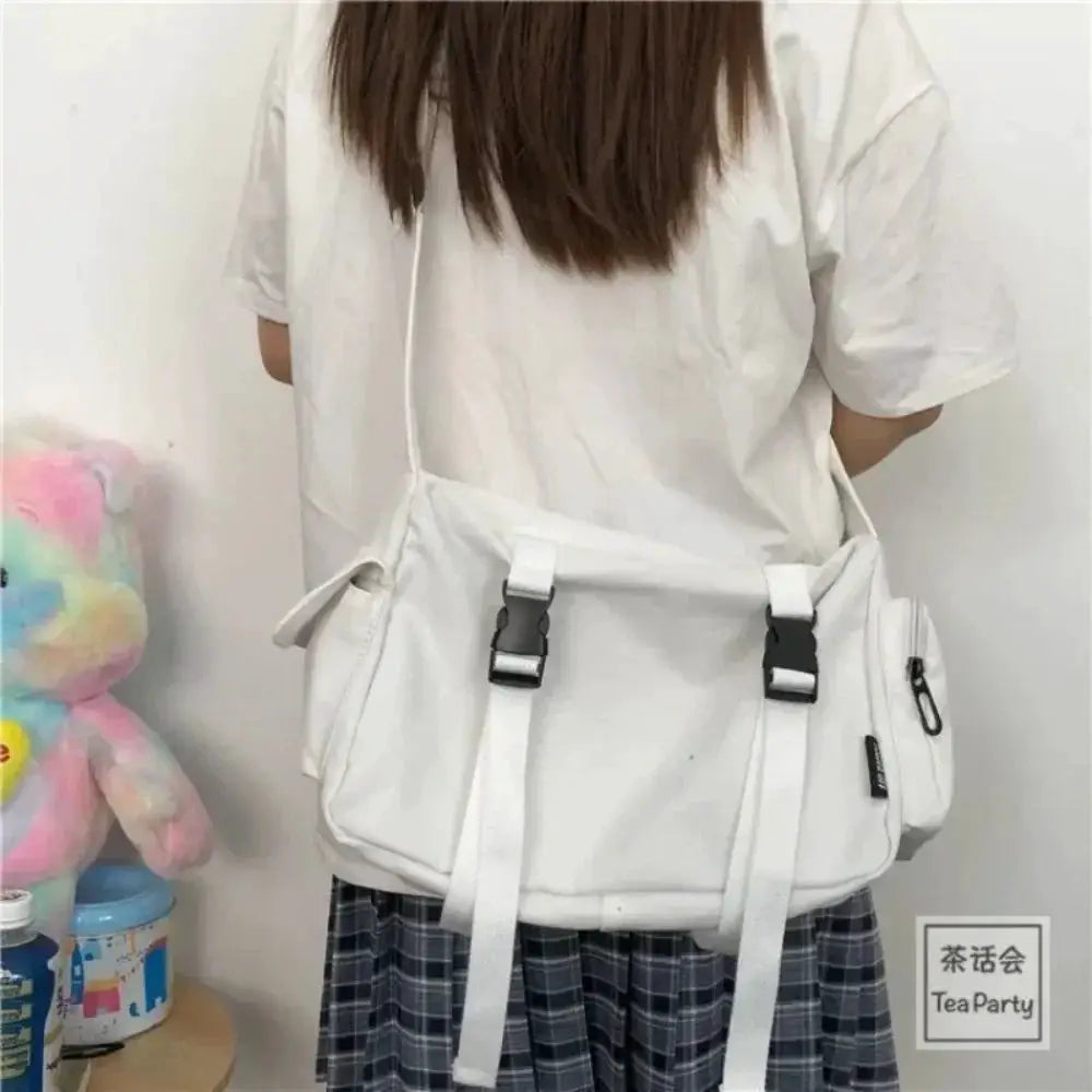 White canvas crossbody bag with two buckle straps and a long adjustable shoulder strap
