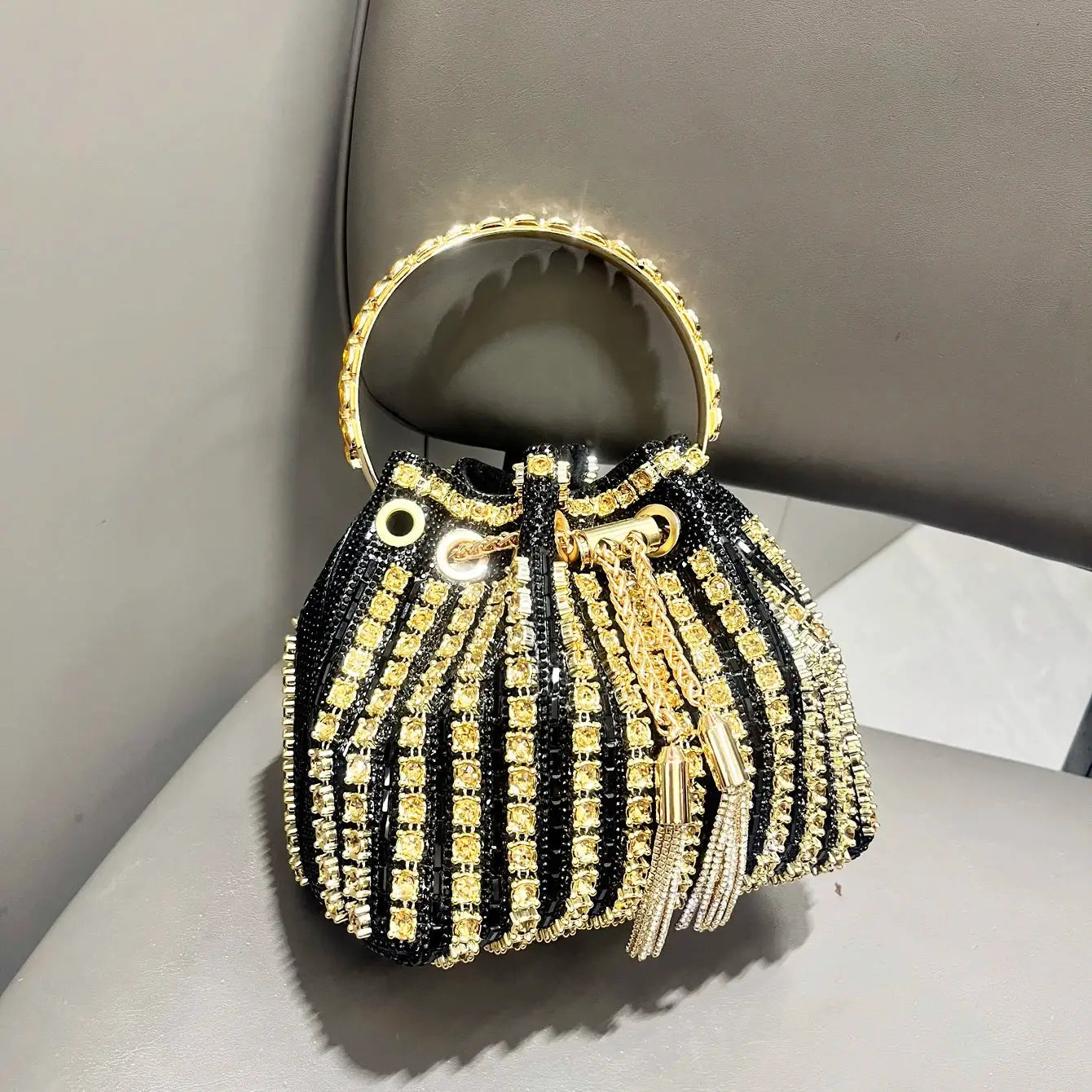 Simples Market black crystal-embellished bucket clutch with gold circular handle and fringe