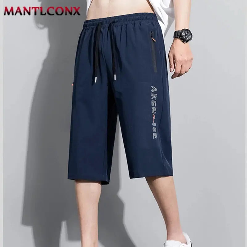 Men's navy blue sports shorts with elastic waist and drawstring, knee-length with zip pockets, MANTLCONX logo.