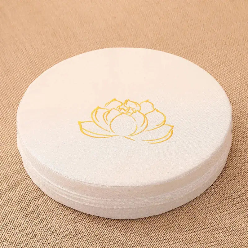 Round white 40x6 cm linen meditation cushion with yellow lotus motif; removable washable cover.