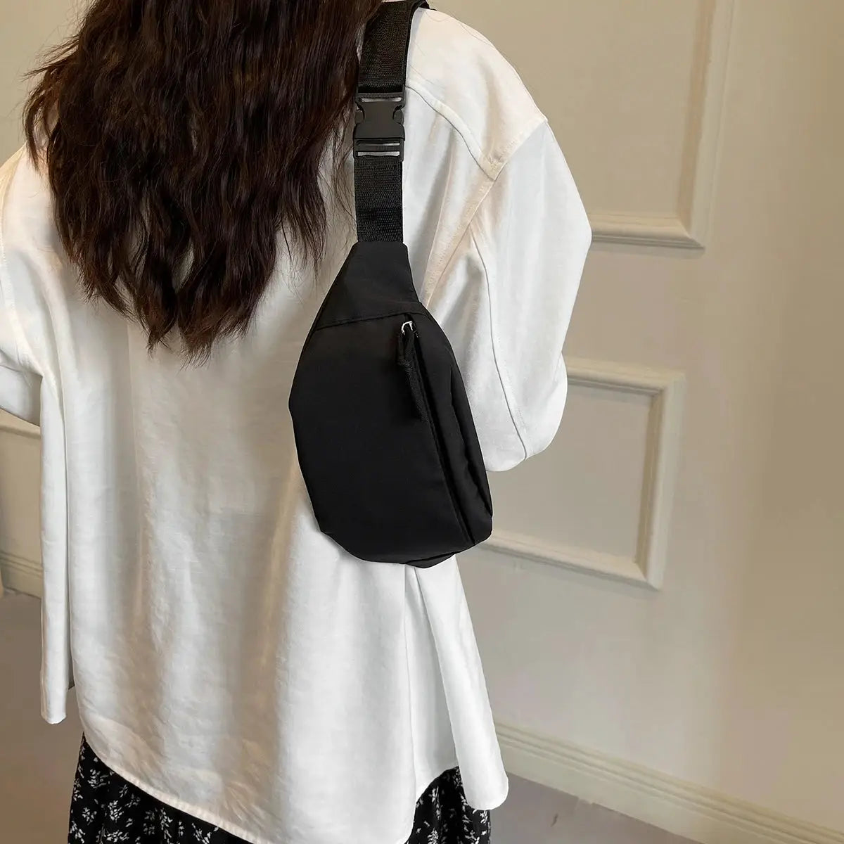 Fanny pack waist bag in black nylon worn crossbody on a white-shirted person.