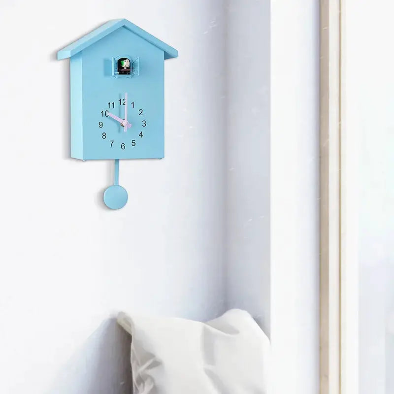 Blue cuckoo wall clock by Simples Market; house-shaped quartz clock with pink hands and pendulum