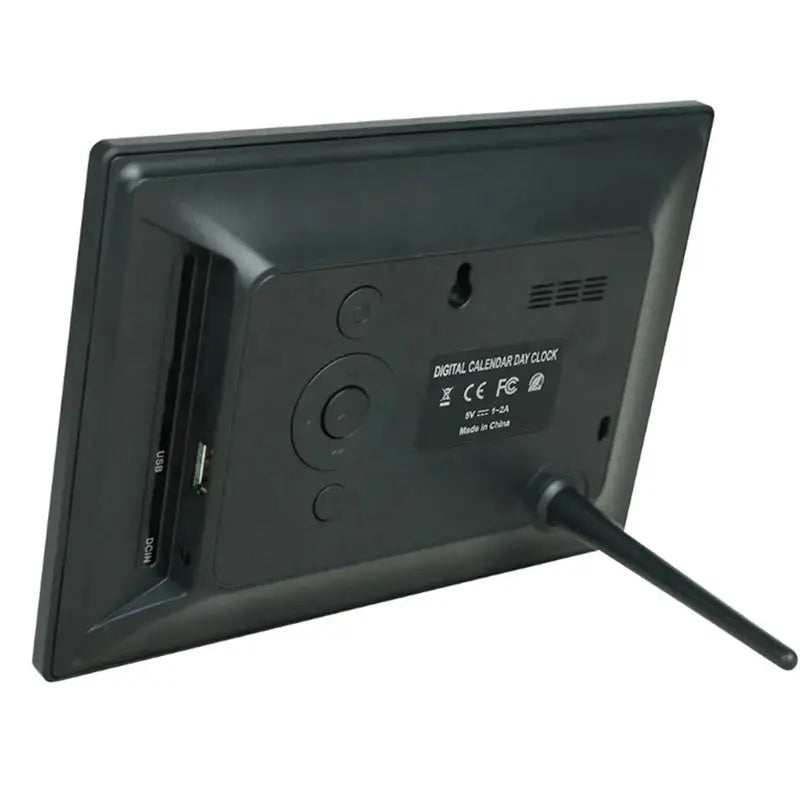 12-alarms digital calendar clock with multilingual display; Simples Market black plastic body with USB and DC IN ports.