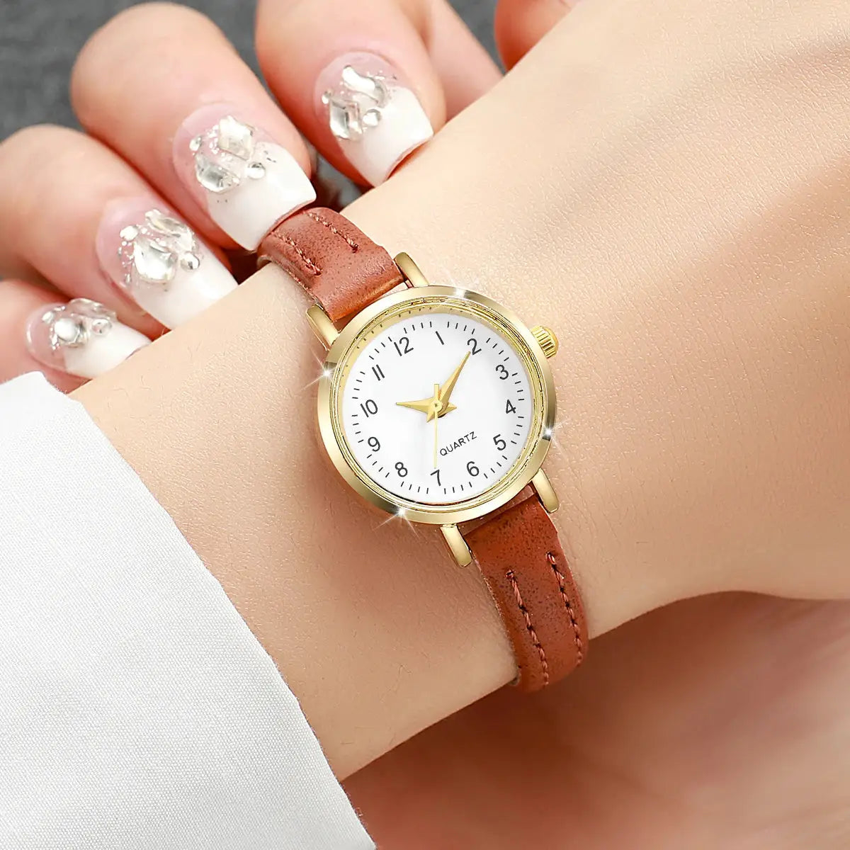 Women's gold-tone watch with white dial and brown leather strap, quartz movement
