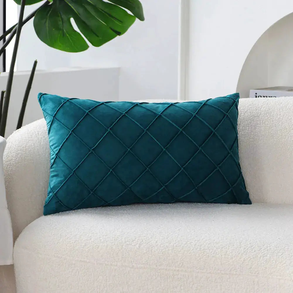 Rectangular teal pillow cover with diamond quilted pattern on a white sofa.