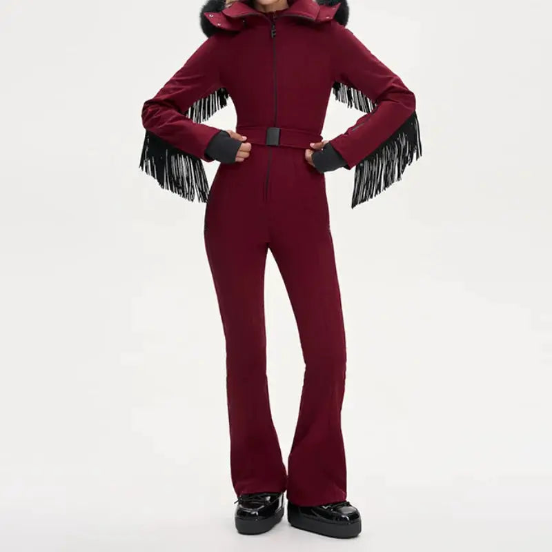 Women’s burgundy one-piece ski suit with faux-fur hood, waist belt and fringe sleeves