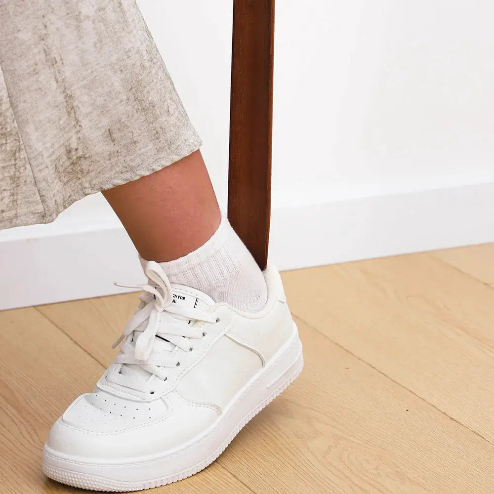 Simples Market shoe horn, premium beech wood with 55cm long handle, shown near a white sneaker on a wooden floor