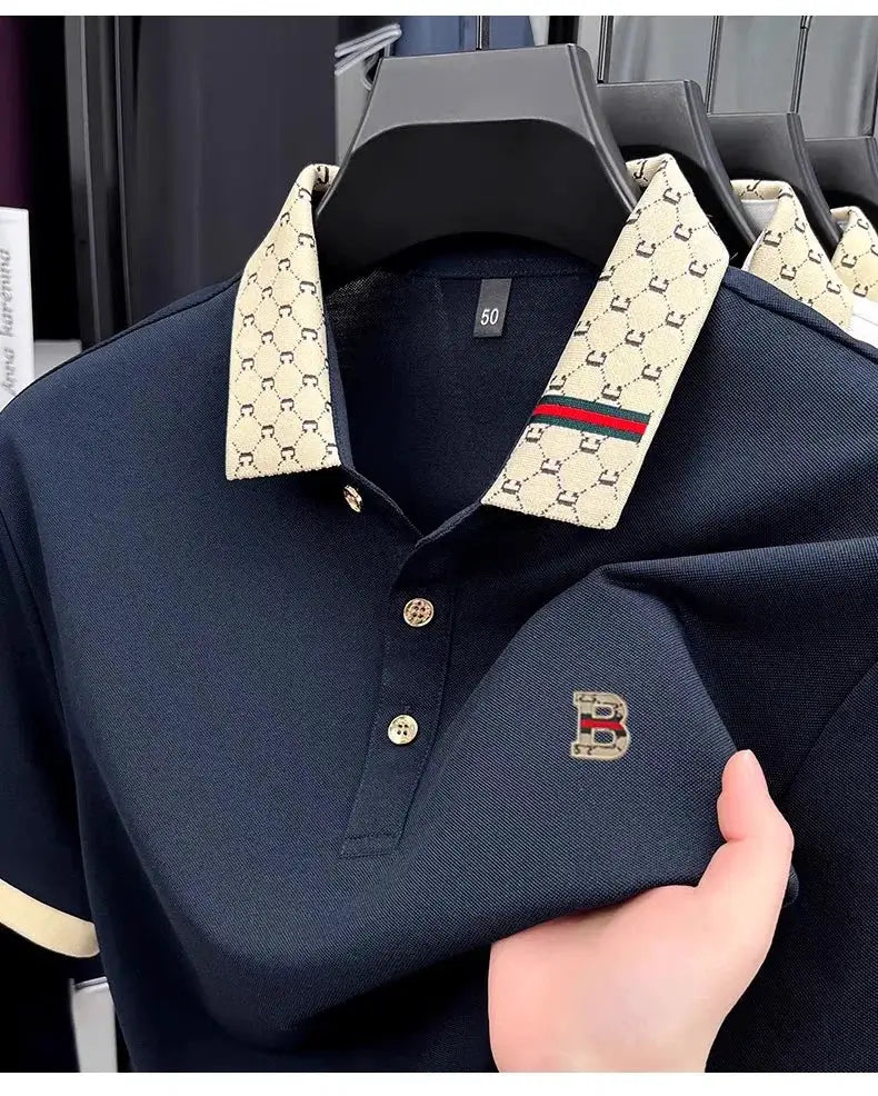 Men's navy short-sleeve polo shirt with beige patterned collar, green-red stripe, gold buttons, B logo embroidery
