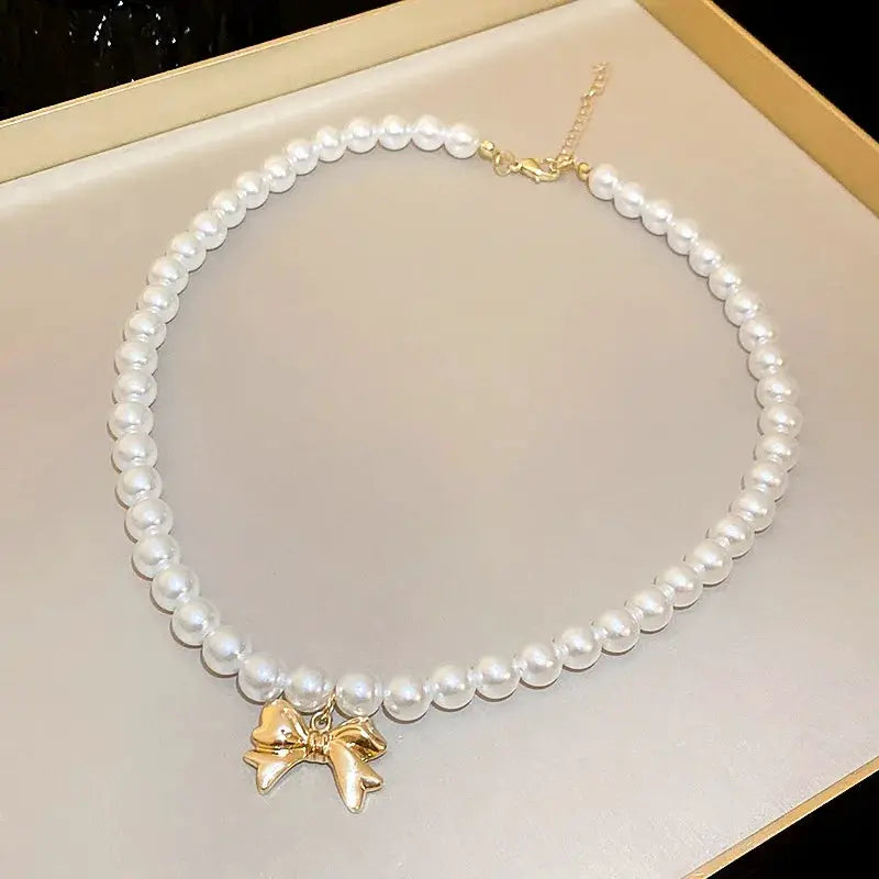 Imitation pearl necklace for women, white pearls with gold bow pendant, collarbone-length chain.