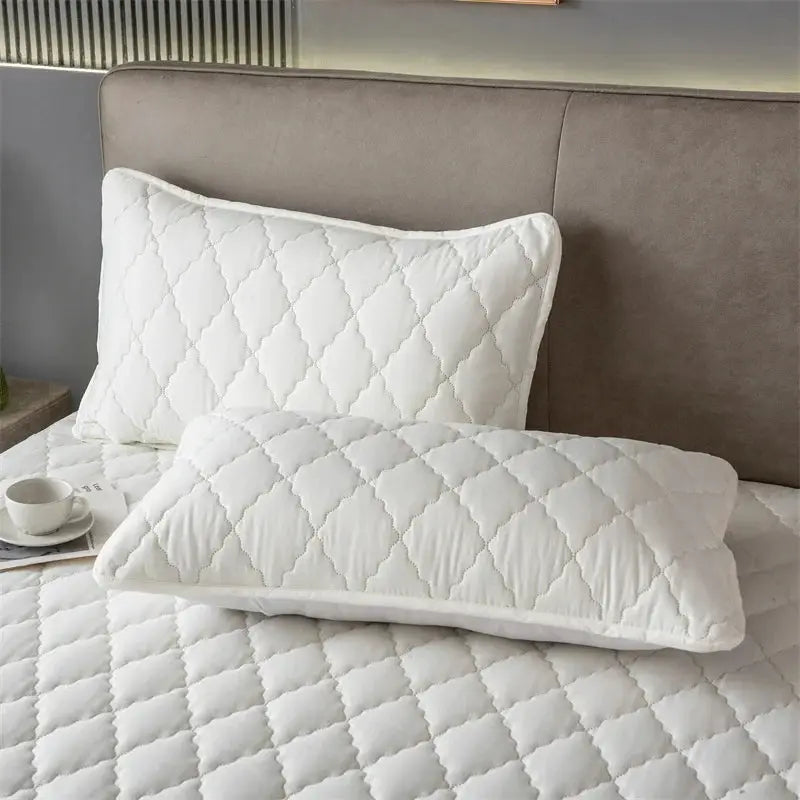 Two white quilted pillowcases on a bed with diamond stitching, offering a clean, soft look for children and pets.