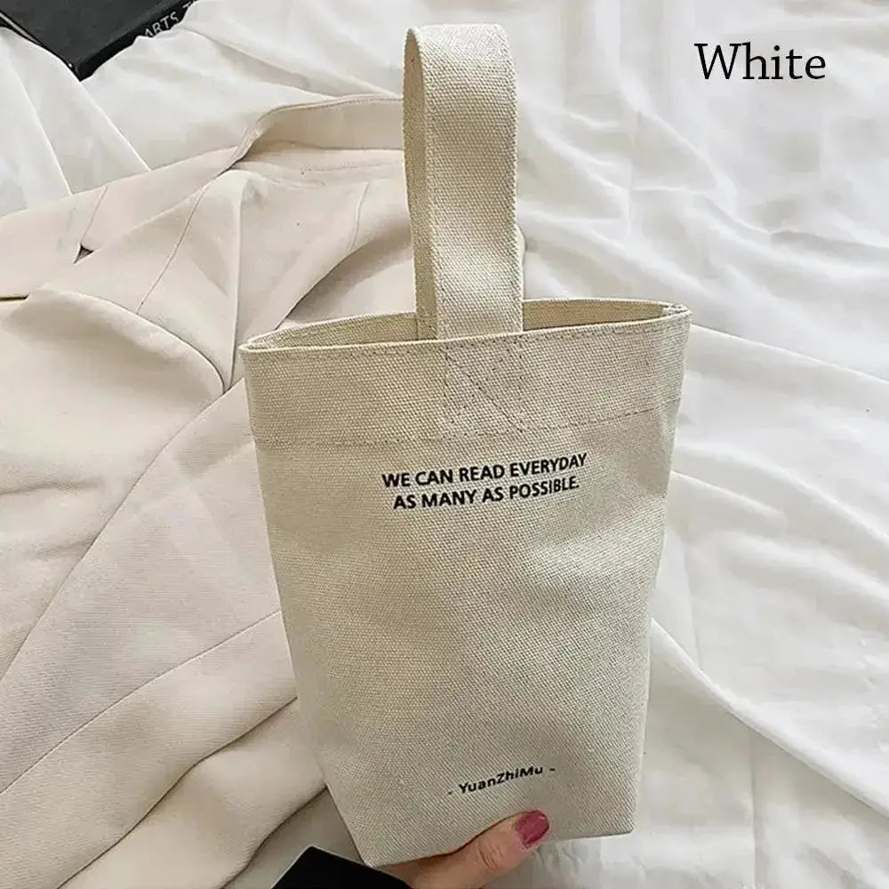 White canvas handbag with a single top handle and printed slogan