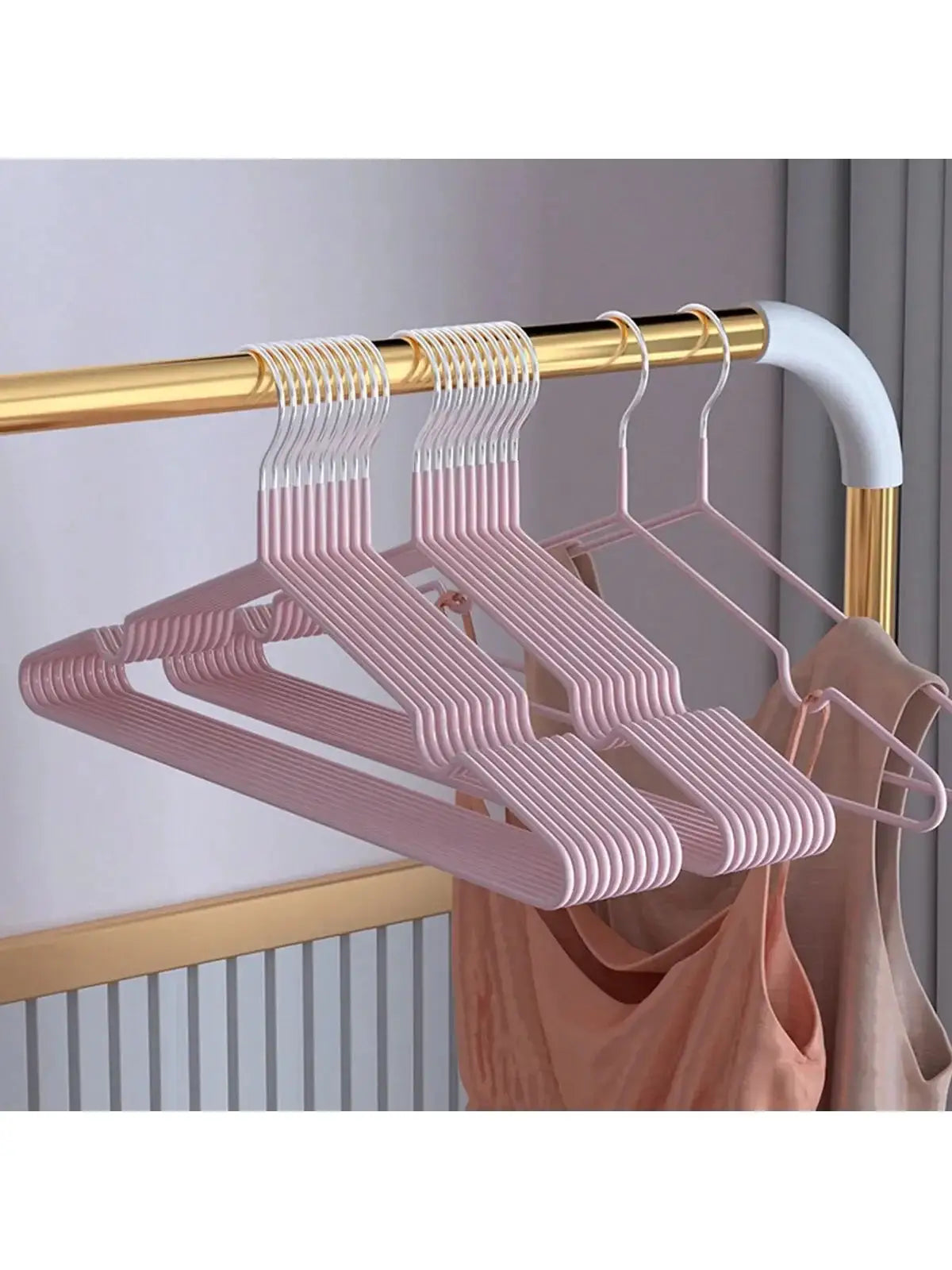 Pink metal seamless anti-slip clothes hangers; multi-piece set on a gold clothing rod.