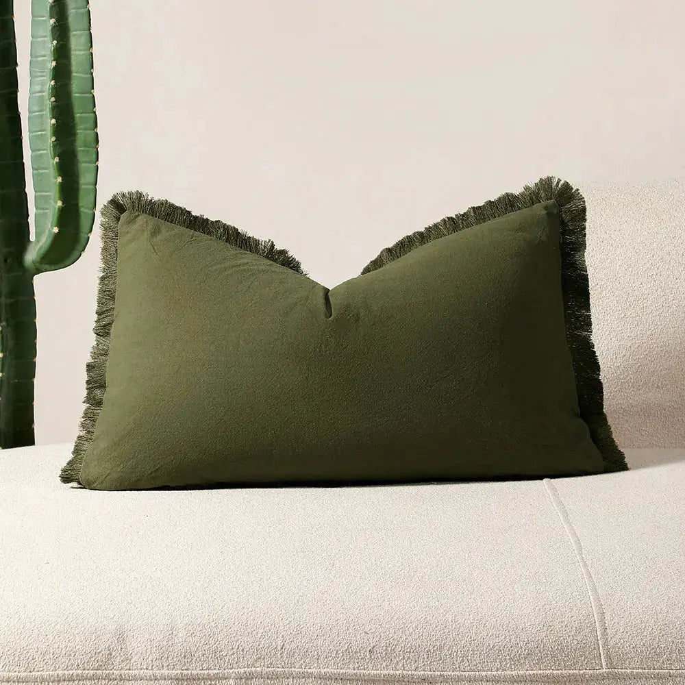 Pillow cover olive green with fringe tassels on beige sofa; boho decorative cushion.