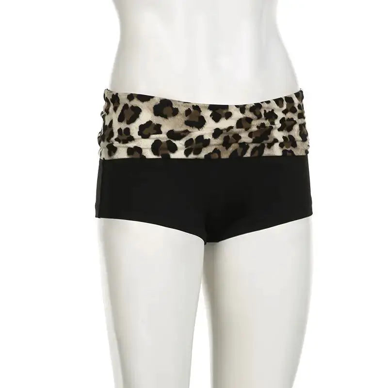 Booty shorts with contrast leopard patchwork waistband and solid black body; low-waist, slim fit