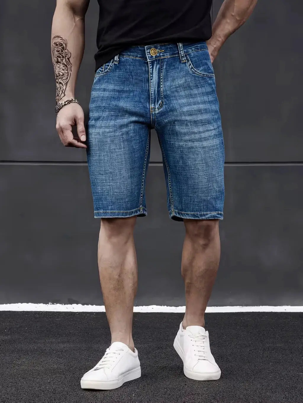Men's knee-length denim shorts in blue stretch denim with a casual straight fit, paired with white sneakers.