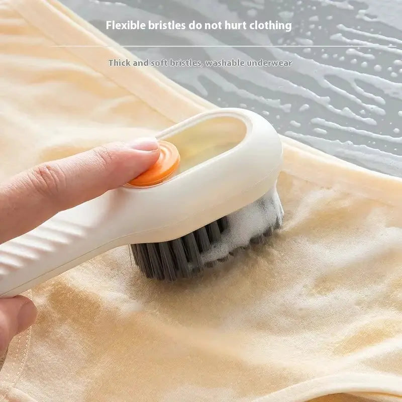 Shoes cleaning brush with white body, orange push button, and soft black bristles.