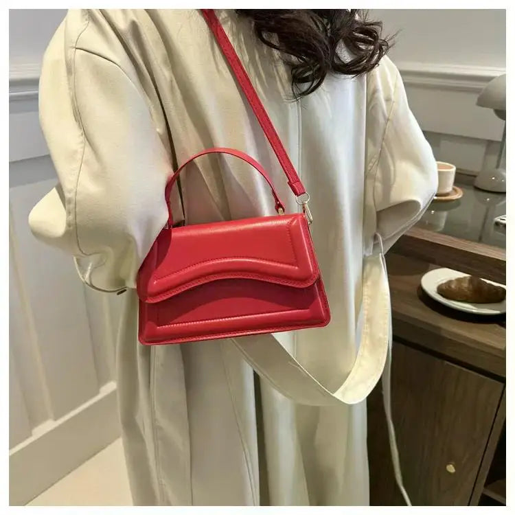 Red PU leather handbag with curved flap, short top handle and crossbody strap