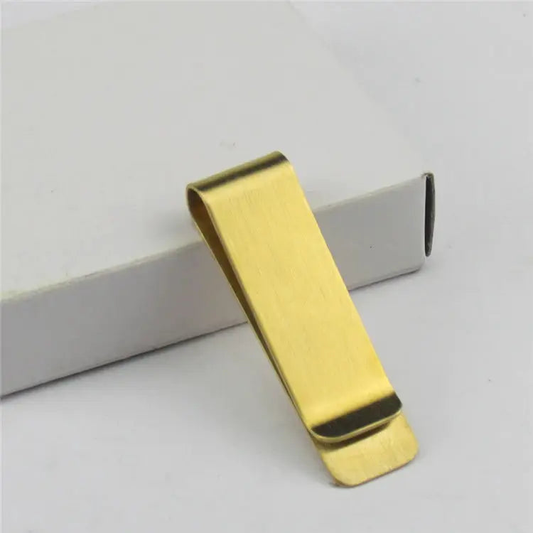 Gold-tone money clip with brushed finish displayed on a white box.