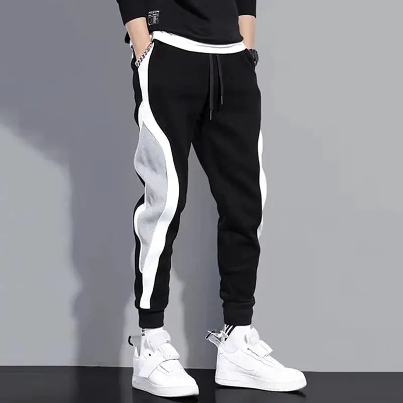 Men's patchwork jogger pants in black with white side panels, elastic drawstring waist, cuffed ankles