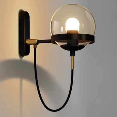 Modern glass ball wall lamp with black metal arm and brass accents, wall-mounted fixture