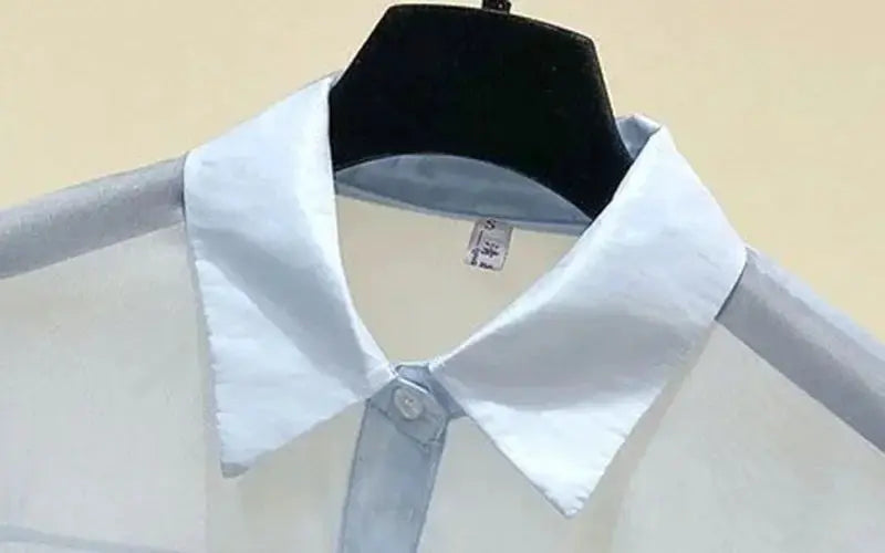 Chiffon blouse with white collar and light blue front button placket, hanging on a black hanger