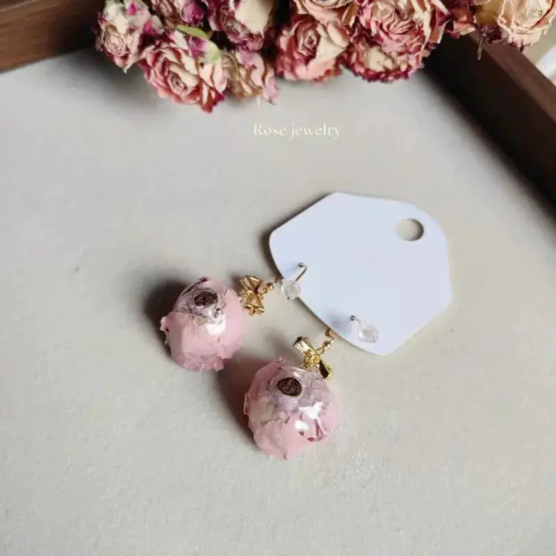 Pair of Elegant Immortal Rose epoxy resin drop earrings with pink rose petals and gold-tone accents