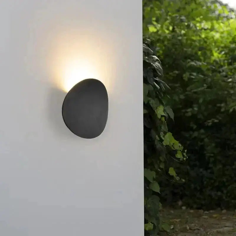 Outdoor LED wall lamp, black circular metal design, waterproof with warm glow on white wall