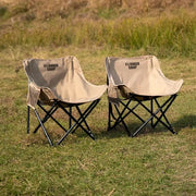 Two beige folding camping chairs with black metal frames and YOUNKER CAMP branding, outdoor grass setting
