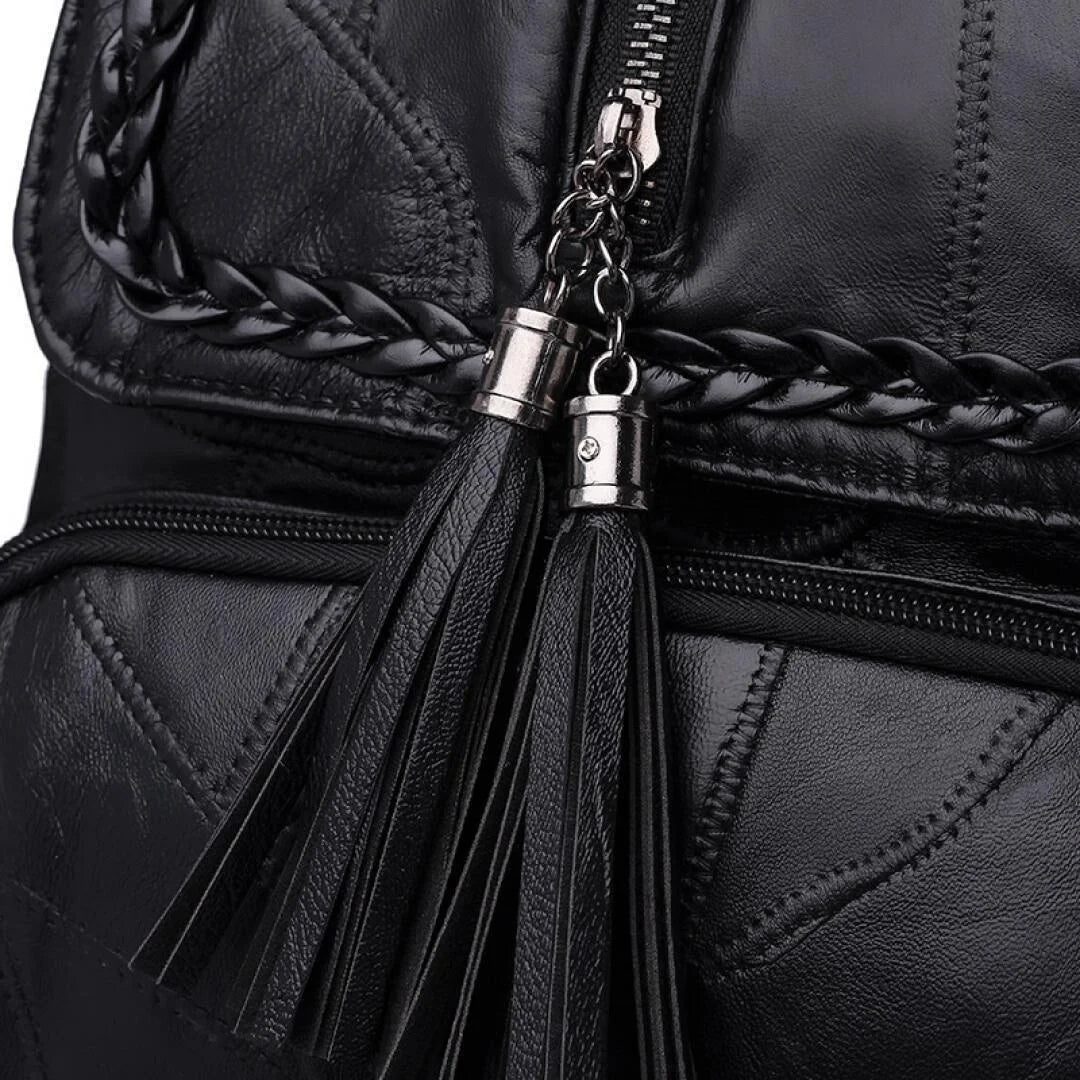 Mini black men's backpack in faux leather with tassel zipper pulls and braided trim.
