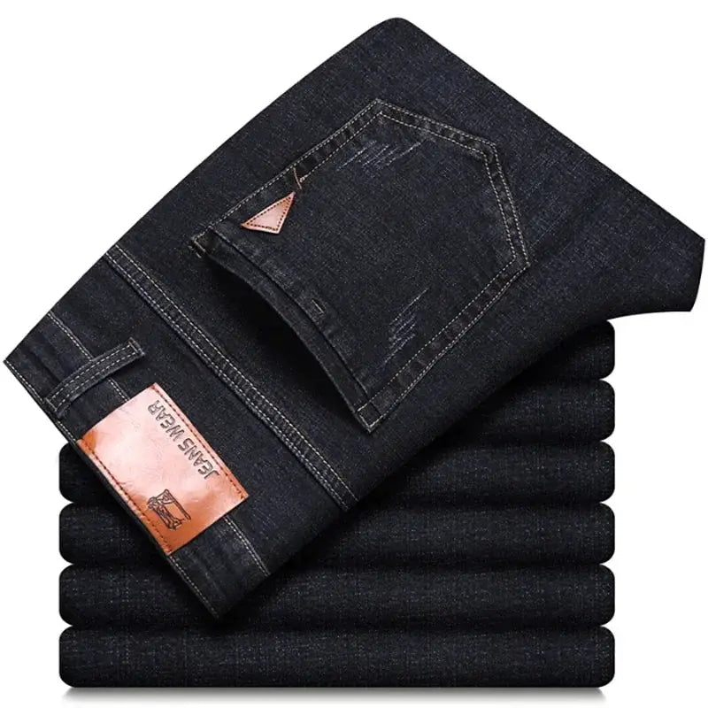 Men's dark denim jeans stacked with folded cuffs and leather brand patch.