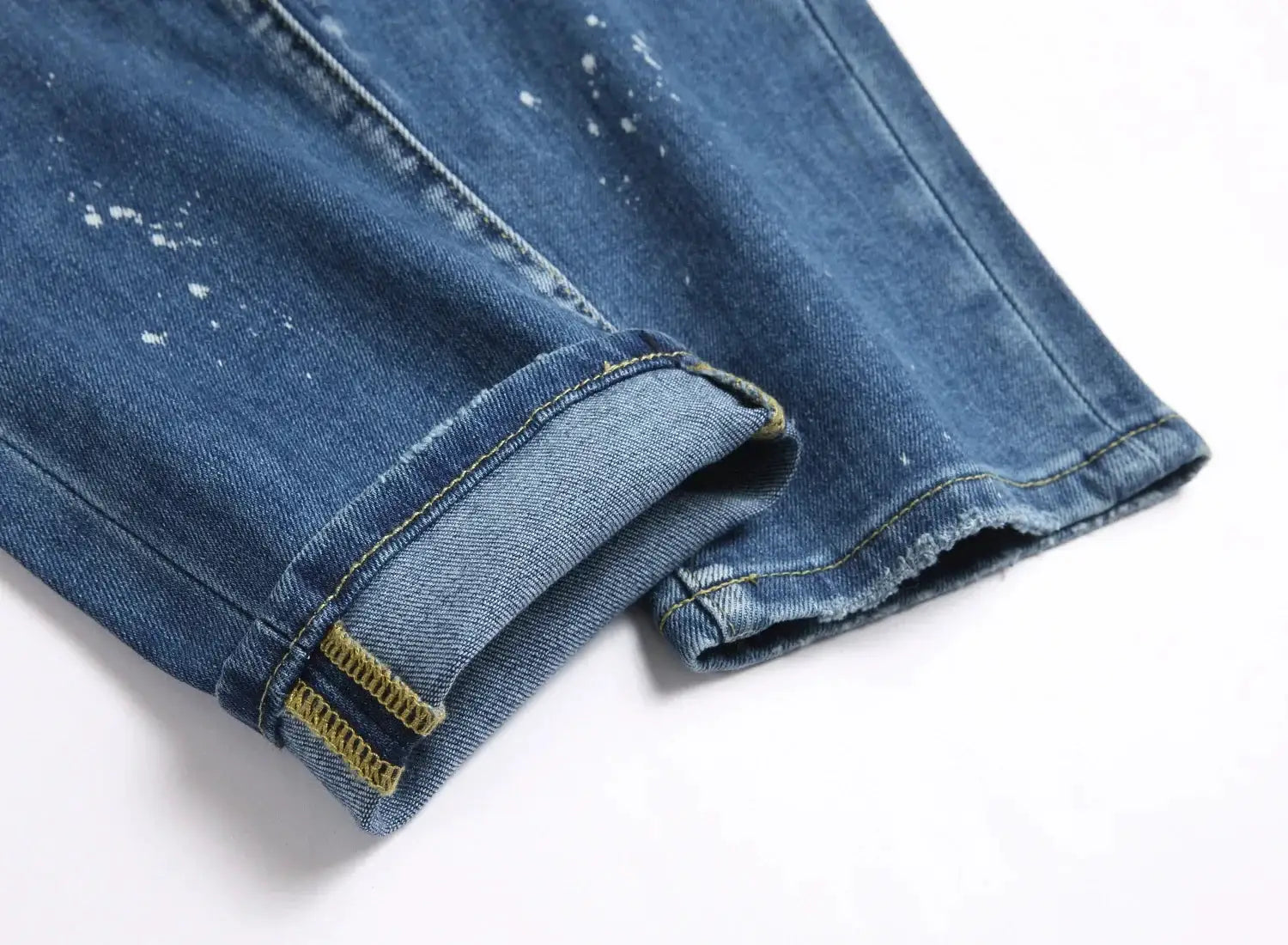 Men's light blue denim jeans with rolled cuff, yellow stitching and paint specks
