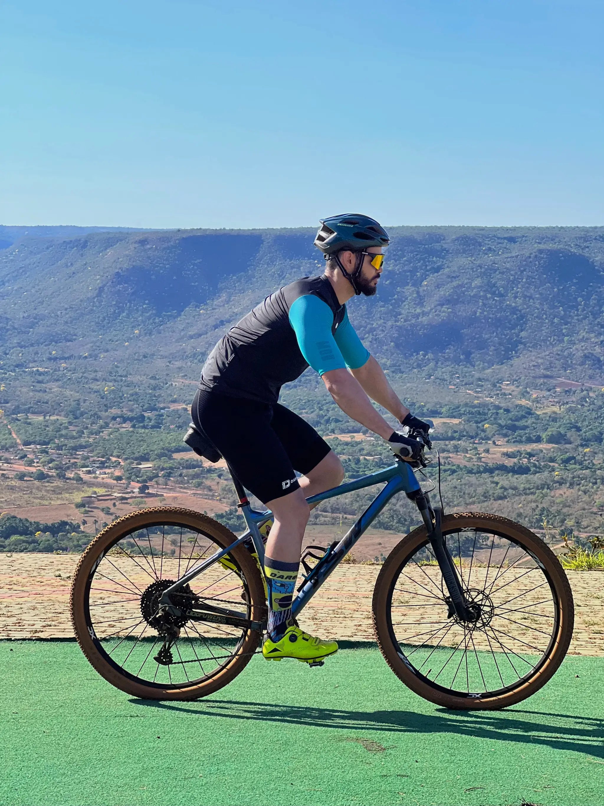 DAREVIE cycling bib shorts for men, black, worn by cyclist on a blue mountain bike.
