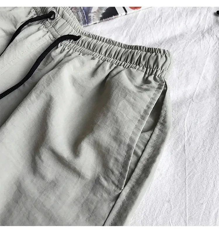 Light gray men's swim shorts with elastic waistband and black drawstring