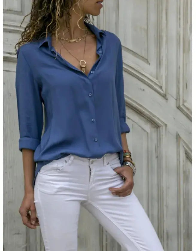 Blue women's loose-fit button-up blouse with polo collar and rolled sleeves, paired with white jeans.