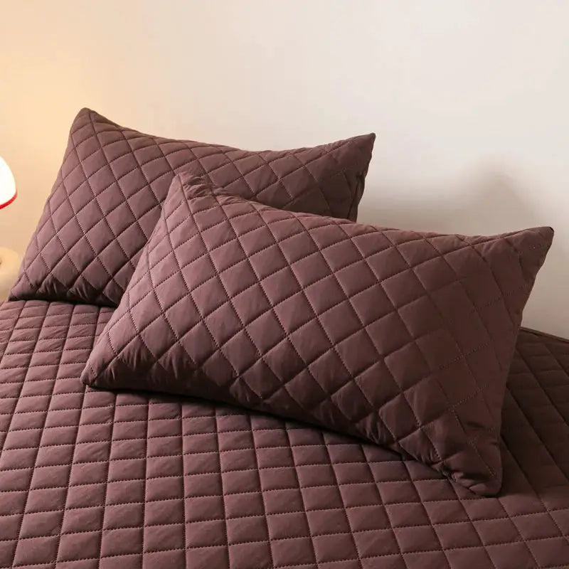 Simples Market quilted cotton pillowcase set in brown plum, 2-piece on bed.