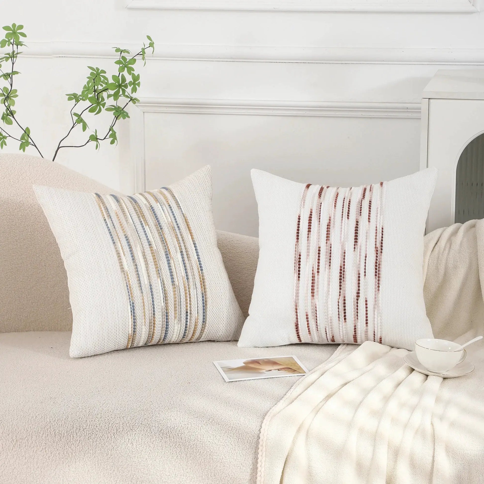 Three decorative boho striped chenille pillow covers, 18x18, white with blue and tan stripes, on sofa